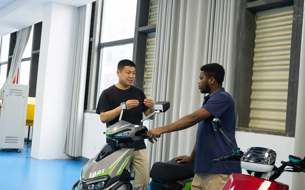 Customer evaluating an electric motorcycle with the Jiangxi Shanxing team